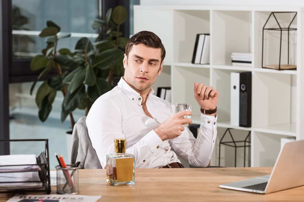 Hombre en despacho sentado. Delante perfume