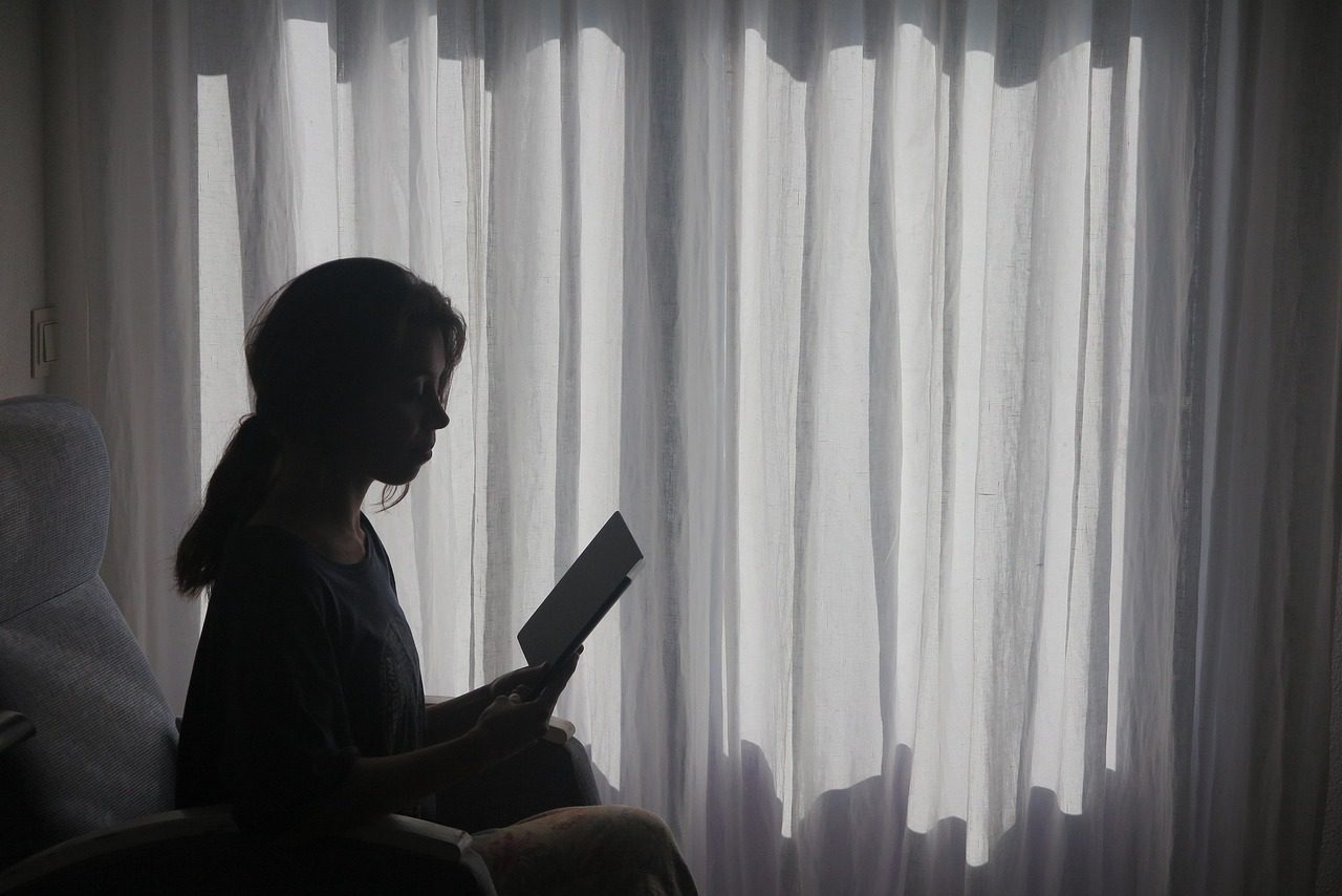 Niña en su cuarto leyendo un libro
