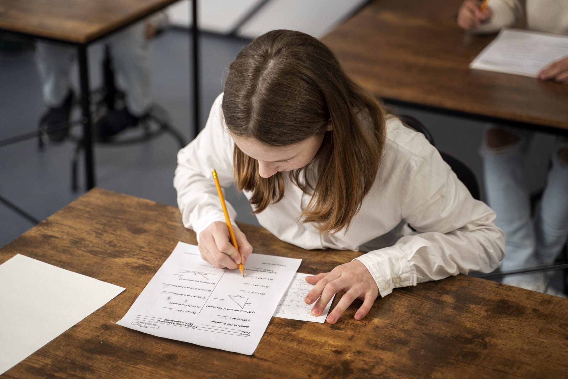 Estudiante de secundaria resolviendo un examen de matemáticas en el aula.